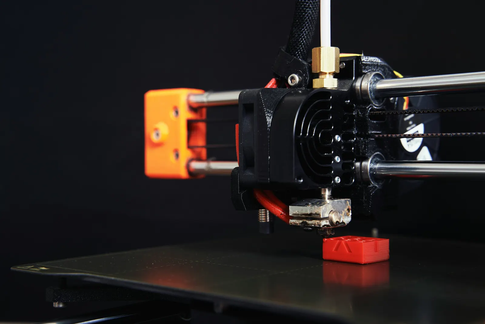 Close-up of a 3D printer nozzle over the build plate